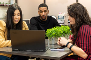 Three students looking at a laptop
