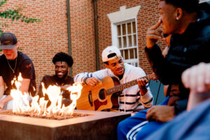 student playing guitar in front of sherman dining hall