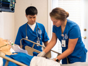 Two nursing students practicing on a dummy